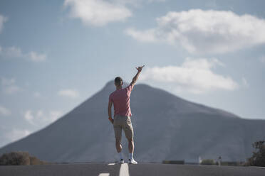 Männlicher Tourist, der auf der Straße in Lanzarote während des Urlaubs ein Horn singt, Spanien - SNF01081