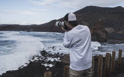 Young male tourist photographing sea at El golfo during vacations, Lanzarote, Spain - SNF01108