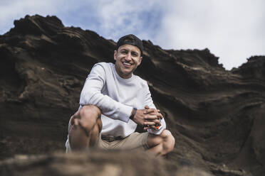 Smiling male tourist against on rock at El golfo, Lanzarote, Spain - SNF01116