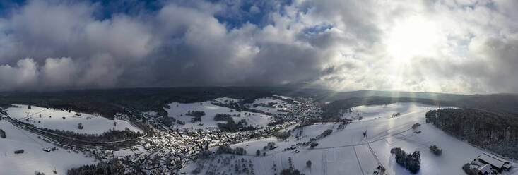 Deutschland, Bayern, Mespelbrunn, Hubschrauber-Panorama der Sonne, die den schneebedeckten Ort im Spessart beleuchtet - AMF09037