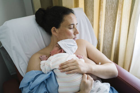 Mother embracing newborn baby boy while resting - MPPF01469