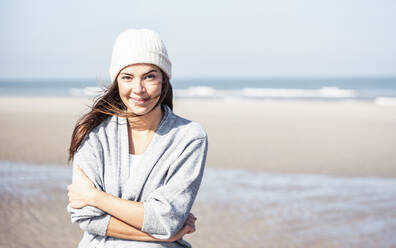 Smiling beautiful woman in cardigan sweater at beach on sunny day - UUF22691