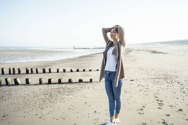 Schöne Frau mit Händen hinter dem Kopf stehend auf Sand am Strand - UUF22704