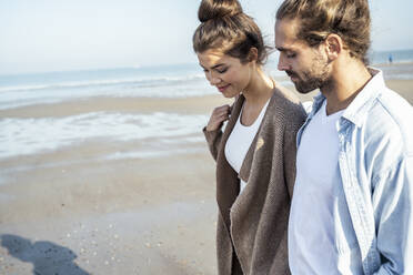 Young couple walking on beach during sunny day - UUF22724