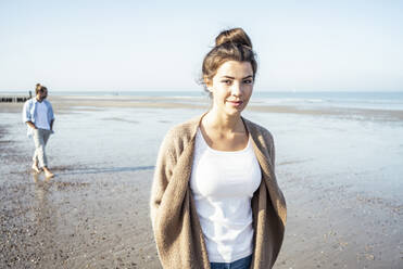 Girlfriend at beach with boyfriend in background during weekend - UUF22728