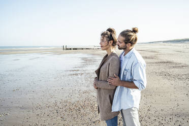 Young girlfriend and boyfriend standing at beach on weekend - UUF22734