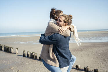 Boyfriend embracing girlfriend while picking up on beach during weekend - UUF22746