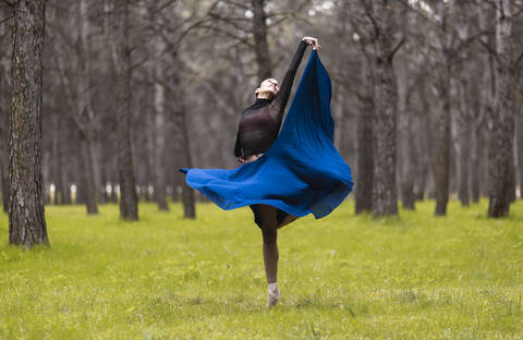 Junge Balletttänzerin, die sich beim Tanzen im Wald dreht, lizenzfreies Stockfoto