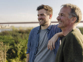 Father and son laughing at riverbank - GUSF05177