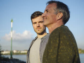 Son and father against sky on sunny day - GUSF05201