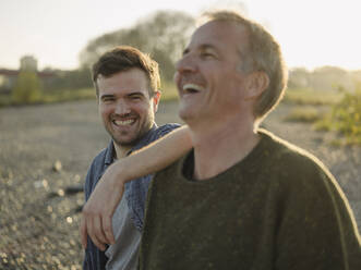 Father and son laughing at riverbank - GUSF05210