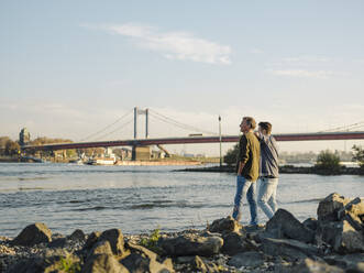 Father and son looking at river while standing against sky - GUSF05213