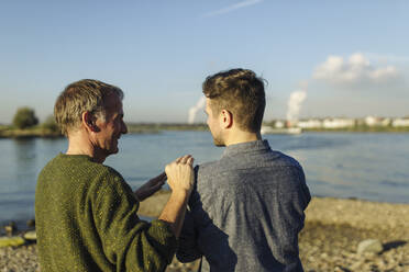 Vater erklärt Sohn am Flussufer an einem sonnigen Tag - GUSF05240