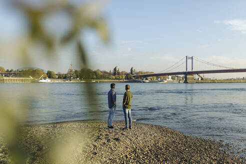 Vater und Sohn bewundern den Fluss gegen den Himmel - GUSF05263