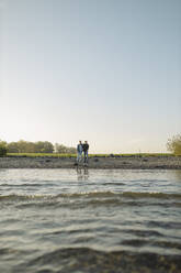 Father and son against clear sky at riverbank - GUSF05268