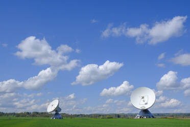 Germany, Bavaria, Raisting, Clouds over Cassegrain antennas standing in field - LBF03329
