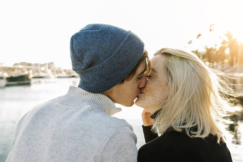 Couple kissing at harbor against sky - XLGF01084