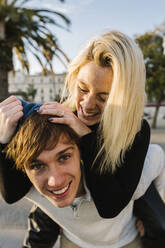 Young man giving girlfriend piggyback ride - XLGF01099