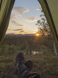 Mature male hiker in tent during sunset in forest at Sweden - HUSF00203