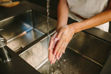 Hohe Winkel von anonymen weiblichen Waschen der Hände mit Seife über Metall Waschbecken in der Küche - ADSF20541