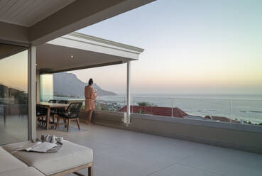 Woman enjoying wine and scenic ocean view from luxury balcony - CAIF30231