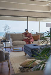 Frau entspannt sich mit digitalem Tablet auf dem Sofa in einem Luxus-Wohnzimmer - CAIF30235