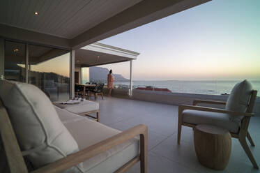 Frau entspannt sich und genießt die Aussicht auf das Meer auf einem luxuriösen Balkon - CAIF30245