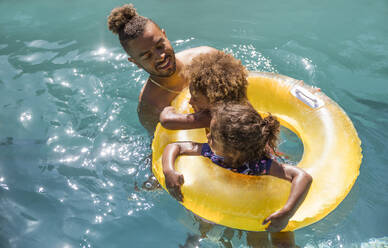 Vater und Töchter im aufblasbaren Ring im sonnigen Sommerschwimmbad - CAIF30260