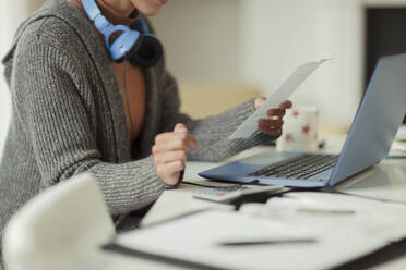 Woman with receipt paying bills at laptop - CAIF30266