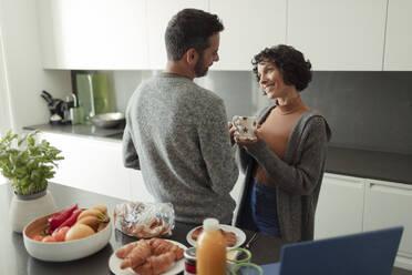 Happy couple enjoying breakfast and coffee in morning kitchen - CAIF30267