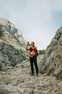 Eine Forscherin benutzt ein Mobiltelefon, während sie am Cares Trail im Nationalpark Picos De Europe, Asturien, Spanien, steht - DMGF00433
