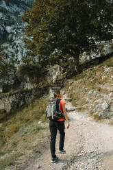 Hiker wearing backpack looking away while walking on Cares Trail at Picos De Europe National Park, Asturias, Spain - DMGF00437