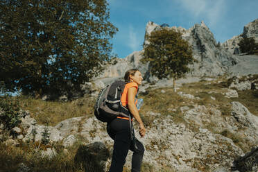 Female hiker wearing backpack hiking on Cares Trail at Picos De Europe National Park, Asturias, Spain - DMGF00438