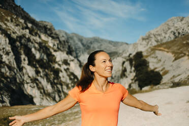 Carefree hiker smiling while standing with arms outstretched at Cares Trail in Picos De Europe National Park, Asturias, Spain - DMGF00443