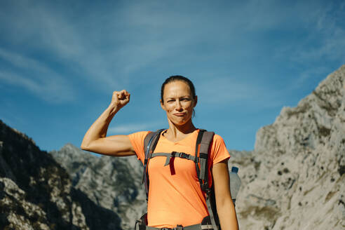 Hiker showing biceps while standing against sky at Cares Trail in Picos De Europe National Park, Asturias, Spain - DMGF00465