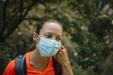 Frau mit Gesichtsschutzmaske, die beim Wandern auf dem Cares Trail im Nationalpark Picos De Europe, Asturien, Spanien, wegschaut - DMGF00469