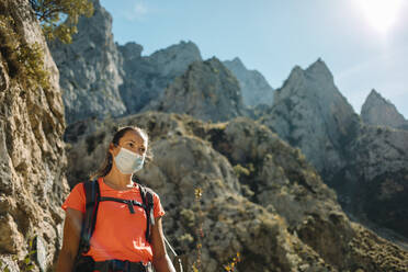 Hiker wearing face mask while hiking on mountain at Cares Trail in Picos De Europe National Park, Asturias, Spain - DMGF00471