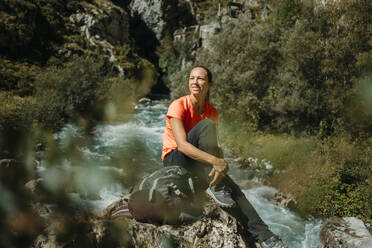 Wanderin mit Rucksack, die sich im Sitzen auf dem Cares Trail im Nationalpark Picos De Europe, Asturien, Spanien, ausruht - DMGF00473