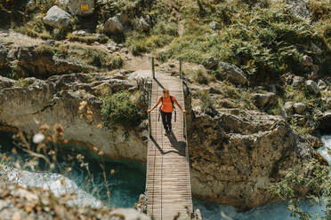 Frau, die auf einer Brücke geht, während sie den Cares Trail im Nationalpark Picos De Europe, Asturien, Spanien, erkundet - DMGF00475