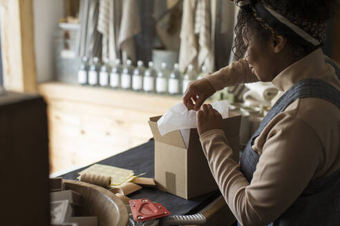 Eine Ladenbesitzerin bereitet ein Paket am Ladentisch vor - CAIF30319