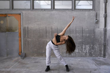 Tänzerin beim Üben an der Wand in einer verlassenen Fabrik - VEGF03728