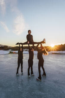 Eiskunstläuferinnen üben auf einem zugefrorenen See bei Sonnenuntergang - RSGF00538