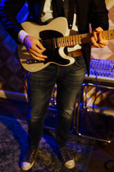 Männlicher Gitarrist beim Üben am Tonmischer im Studio - PGF00395