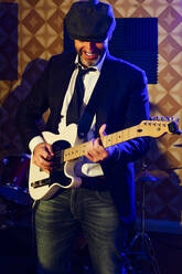 Smiling musician playing guitar at studio - PGF00396