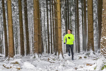 Junge Frau läuft im Winter auf einem Waldweg - STSF02805