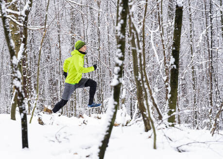 Sportler läuft im Winter auf Schnee im Wald - STSF02811