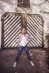 Girl with hand on hip standing against barn - DHEF00513