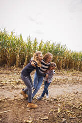 Friends playing together while standing against corn field - DHEF00542