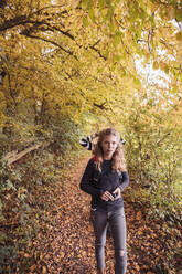 Mädchen beim Wandern mit Freund im Hintergrund im Wald im Herbst - DHEF00545