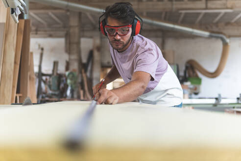 Männlicher Tischler mit Maßband bei der Arbeit in der Werkstatt - JAQF00213